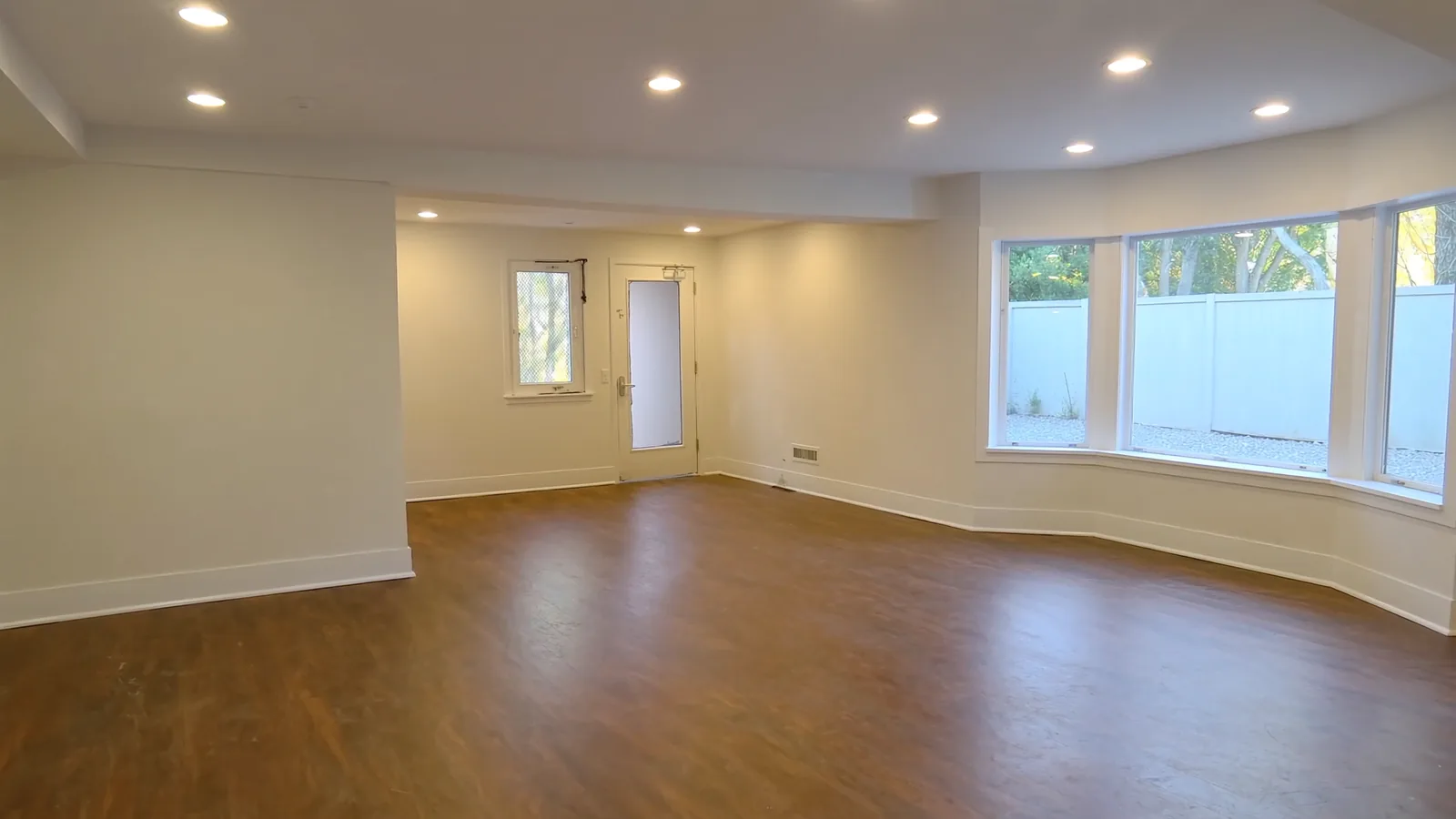 The same garage after conversion to living space — LVP flooring, drywall, mini-split HVAC, natural light